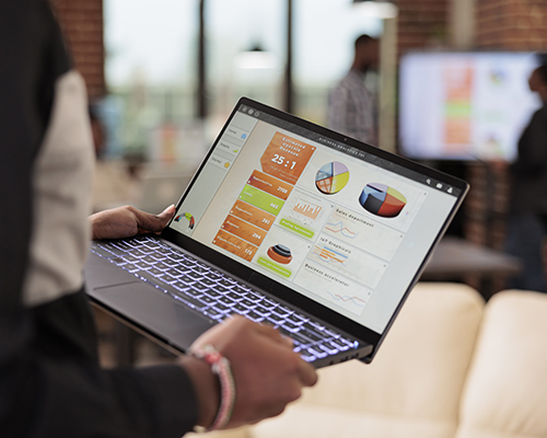 Employee holding laptop with business diagrams